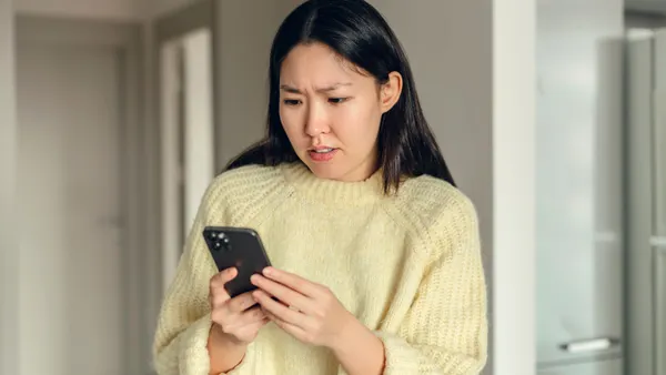 A young woman looks concerned at her phone.