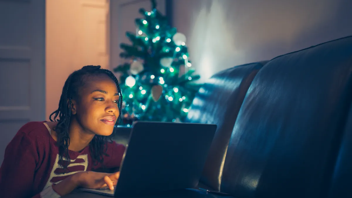 Person shops online with a Christmas tree in the background.