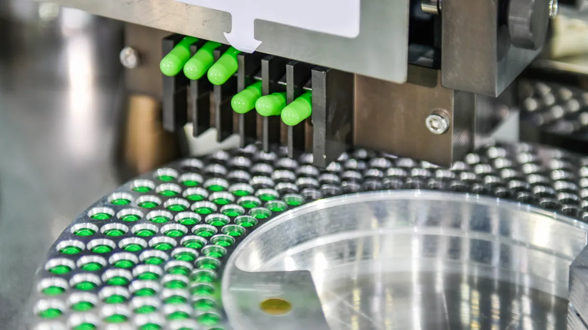 Green capsule medicine pill fall out of a production line.