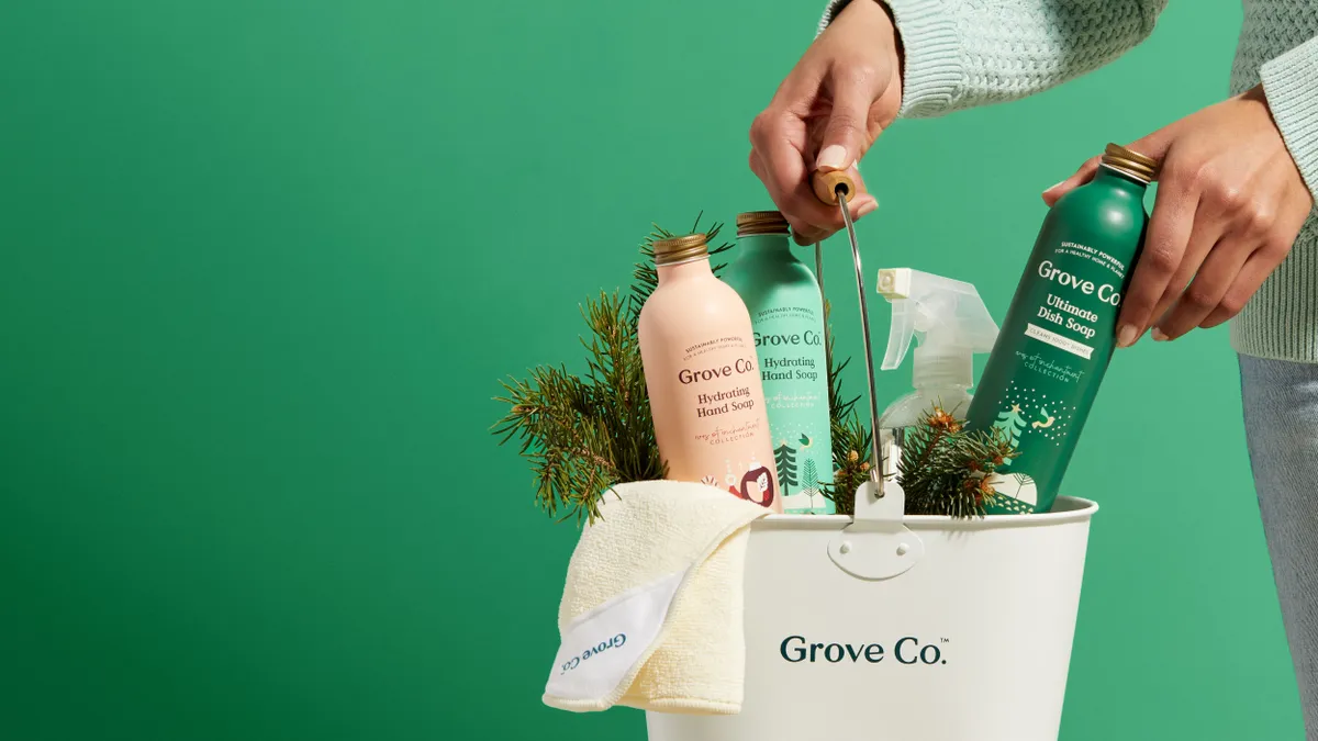 Three multi colored Grove Collaborative bottles displayed in a white bucket and a green backdrop