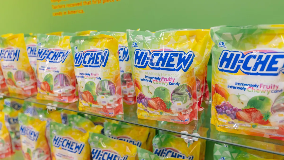 Two rows of green and yellow Hi-Chew candy on a store shelf.