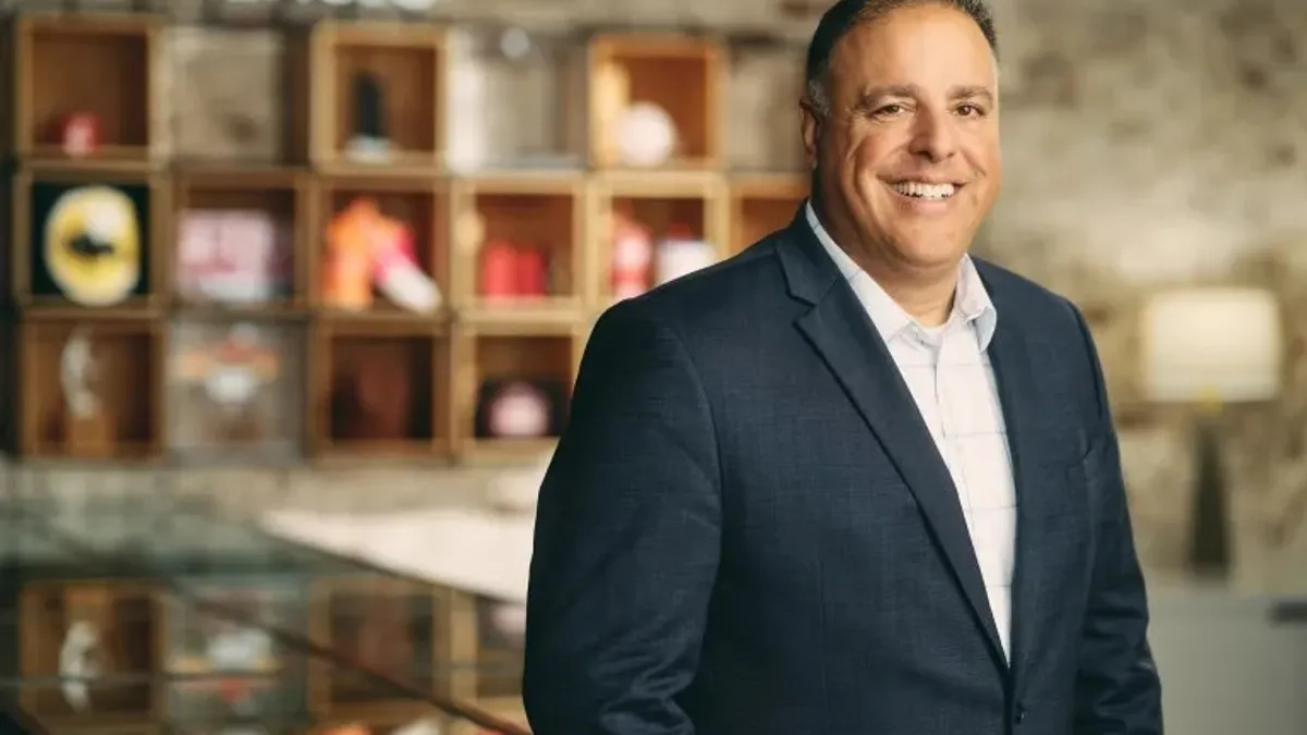 Jason Maceda, Inspire Brands' new chief development officer, smiles in front of some branded items.