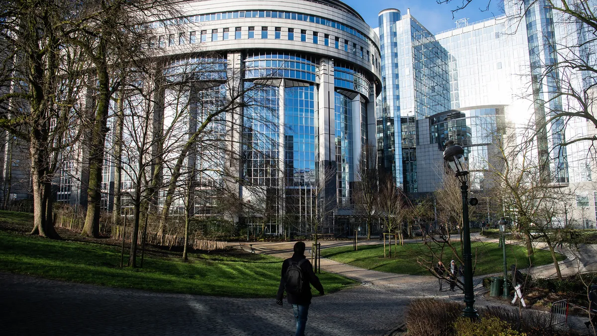 A view of the building for the European Parliament. A person walks in front of it.