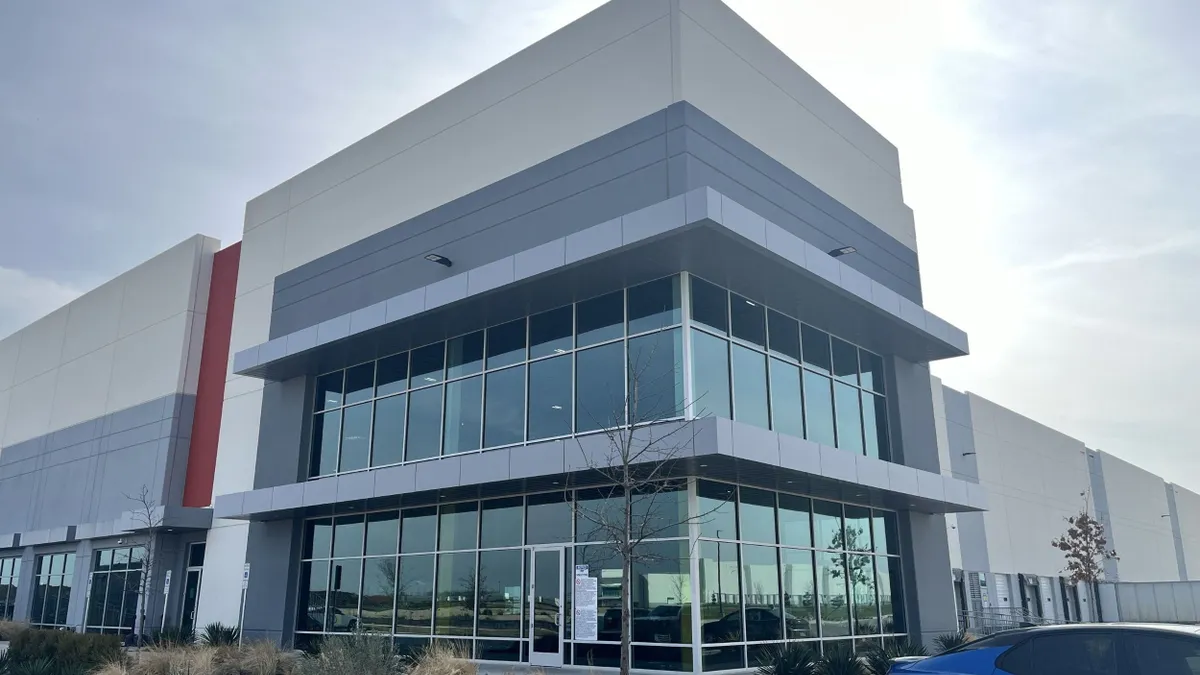 The corner of a gray and beige glass building.