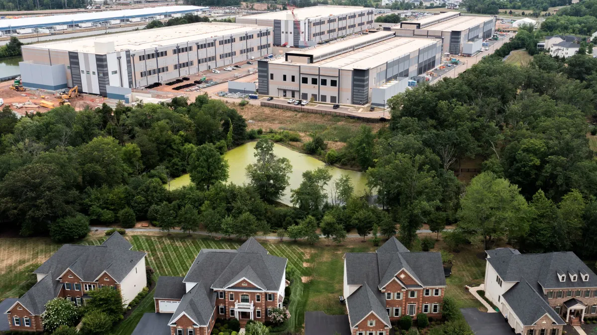 An aerial view of houses near large warehouse-looking buildings.