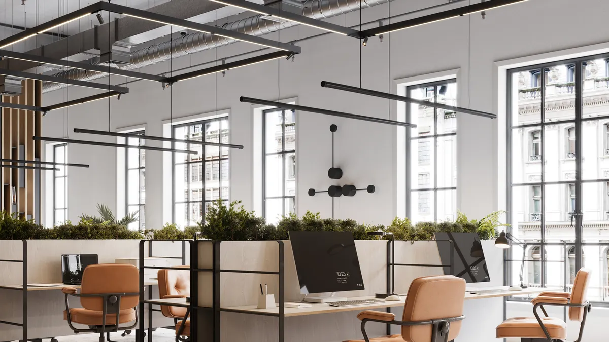 A modern office space with hanging lights and shared deskspace.