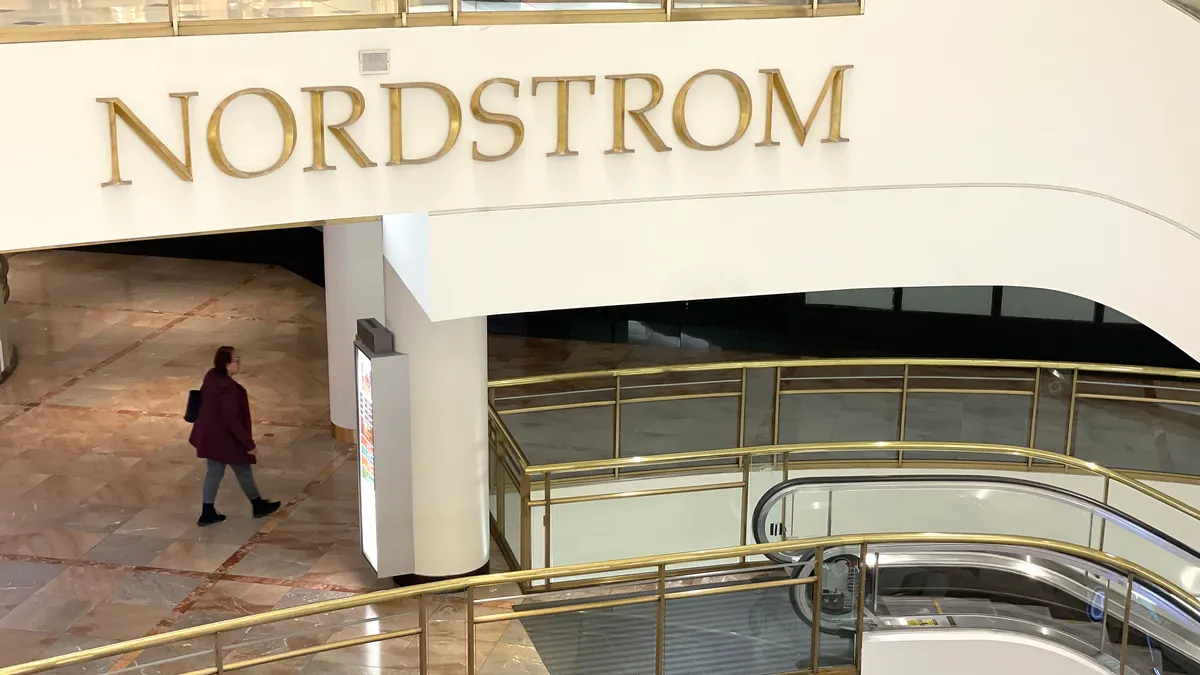 An aerial view of a Nordstrom mall store. A person walks under the sign reading "Nordstrom."