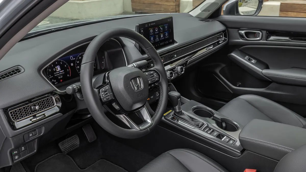 The black interior of a 2022 Honda Civic showing the dashboard and steering wheel.