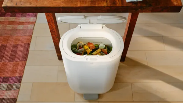 Overhead view of a sleek bin with a lid and food scraps piled inside.