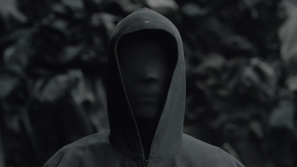 Image of a person in a back face mask and hood.