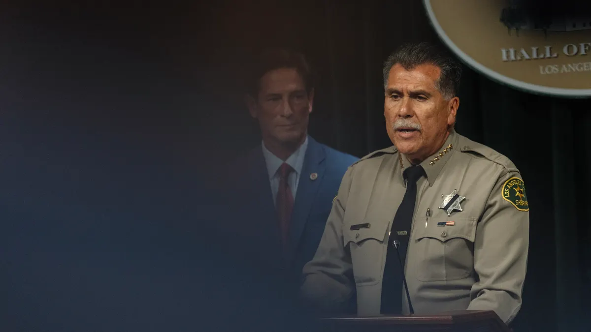 Person wearing law enforcement uniform with star badge speaks at a podium