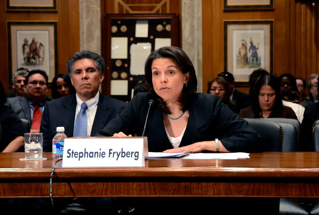 Stephanie Fryberg speaks into a microphone behind a placard with her name