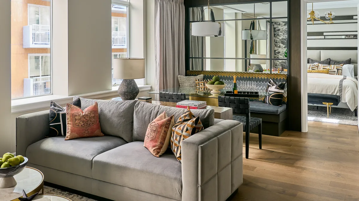 A living room with a couch and a bedroom behind a partition.