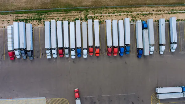 Trucks stand in a row at the rest area on the highway in aerial view.