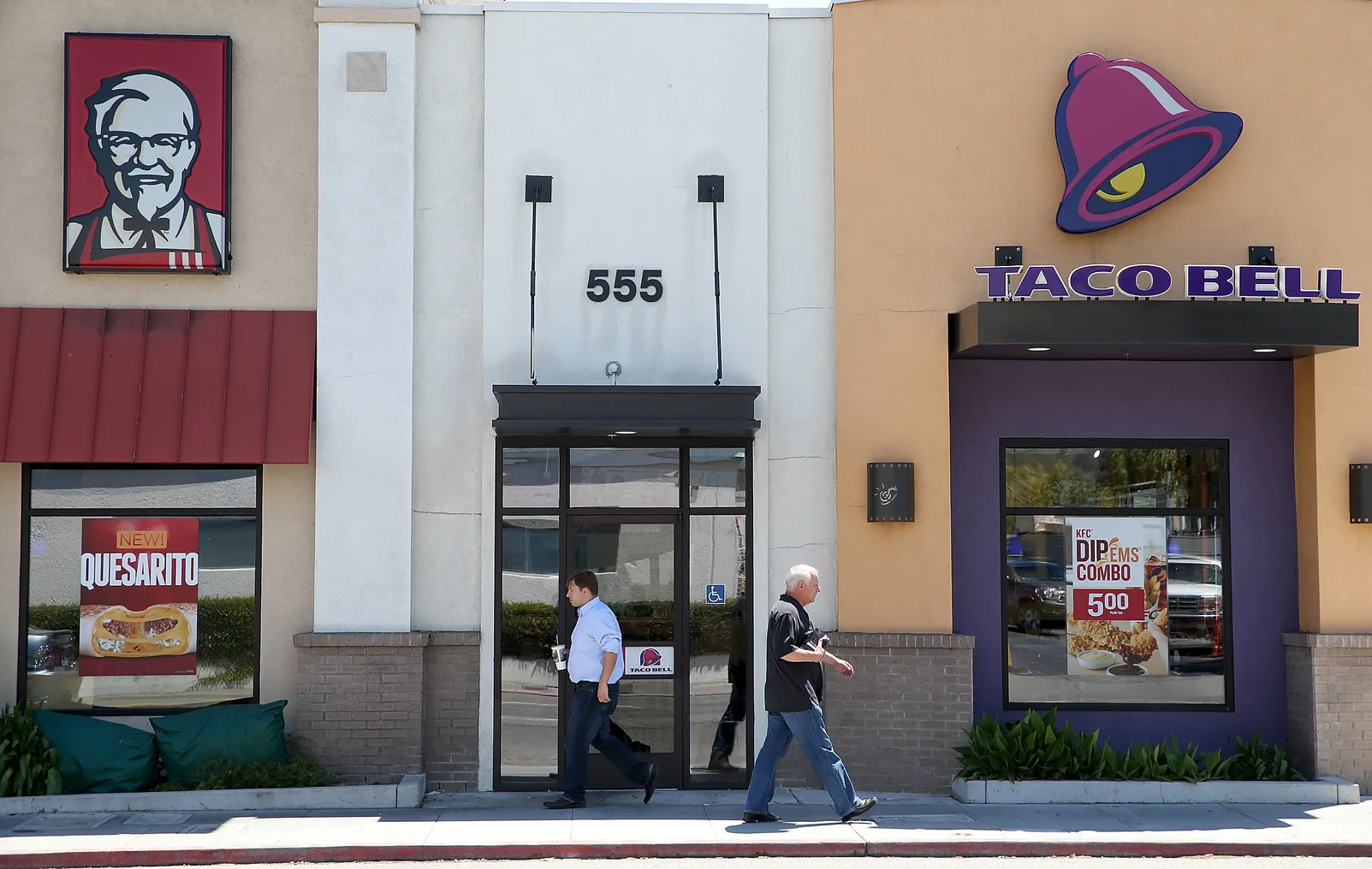 Pedestrians walk by a KFC and a Taco Bell restaurant on July 2, 2014 in San Rafael, California.