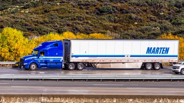 A Marten Transport truck driving on the freeway with vegetation in the background.