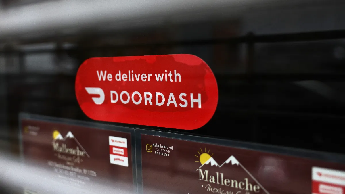 A red sticker on a restaurant window announcing the restaurant offers delivery with DoorDash.