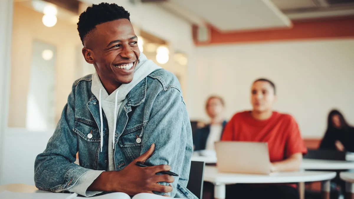 Smiling male student sitting in university classroom.