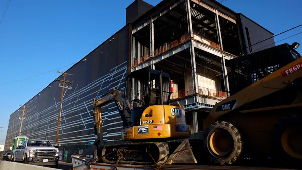 A photo shot at an upward angle of an under-construction building under a blue sky.