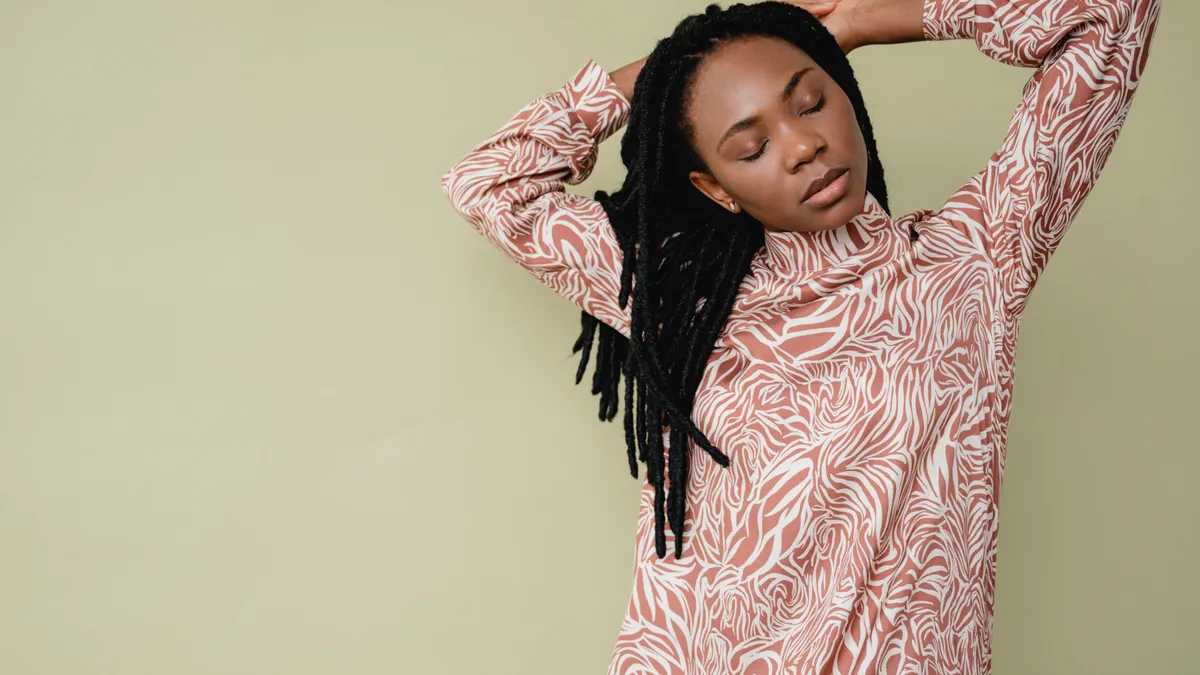 A Black woman with dreads stretches her arms