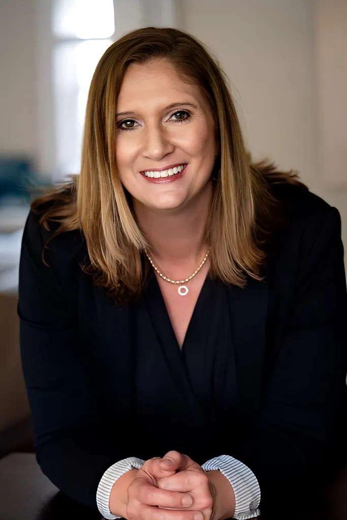 A head and shoulders photo of a person in a room with white walls.