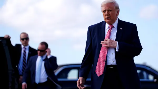 President Donald Trump walks while adjusting his tie.