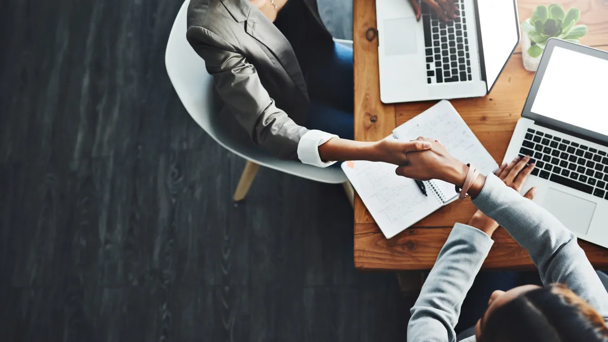 High angle shot of two business people shaking hands in an office