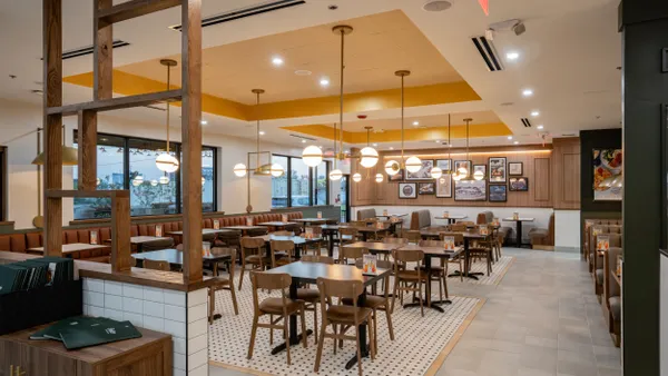 A picture of a restaurant interior. Empty tables, white tile, green walls.