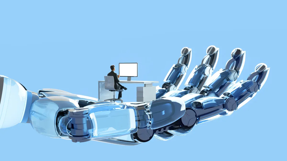 A man sits at a computer desk which is in a giant robot hand.