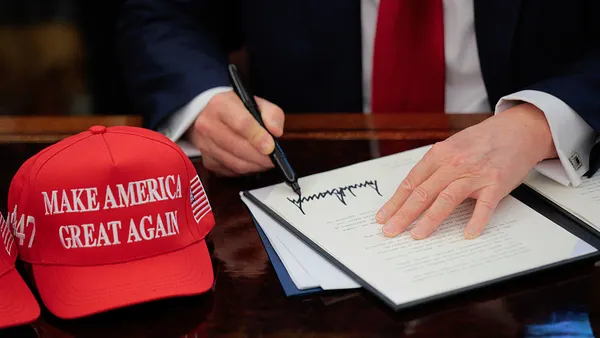 MAGA hats sit next to an executive order being signed by President Donald Trump