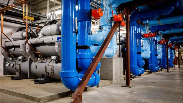 Five industrial chillers and piping in a basement.
