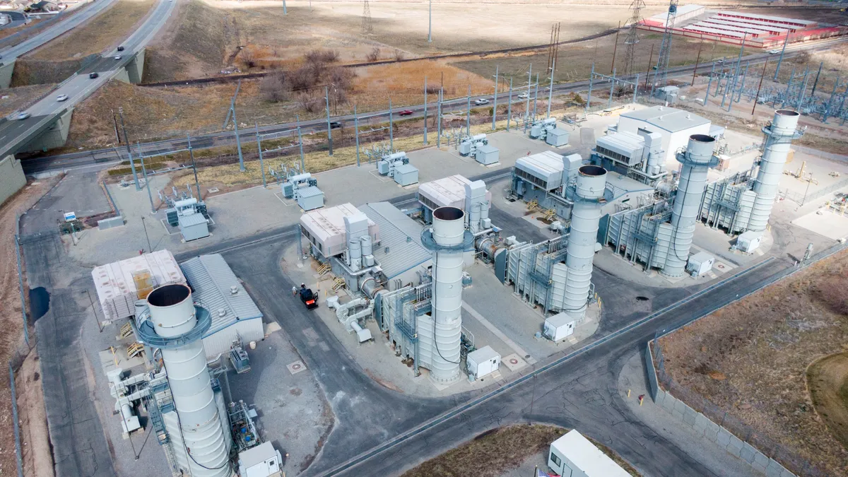 An aerial view of five smoke stacks and industrial equipment with a road and highway in the background.