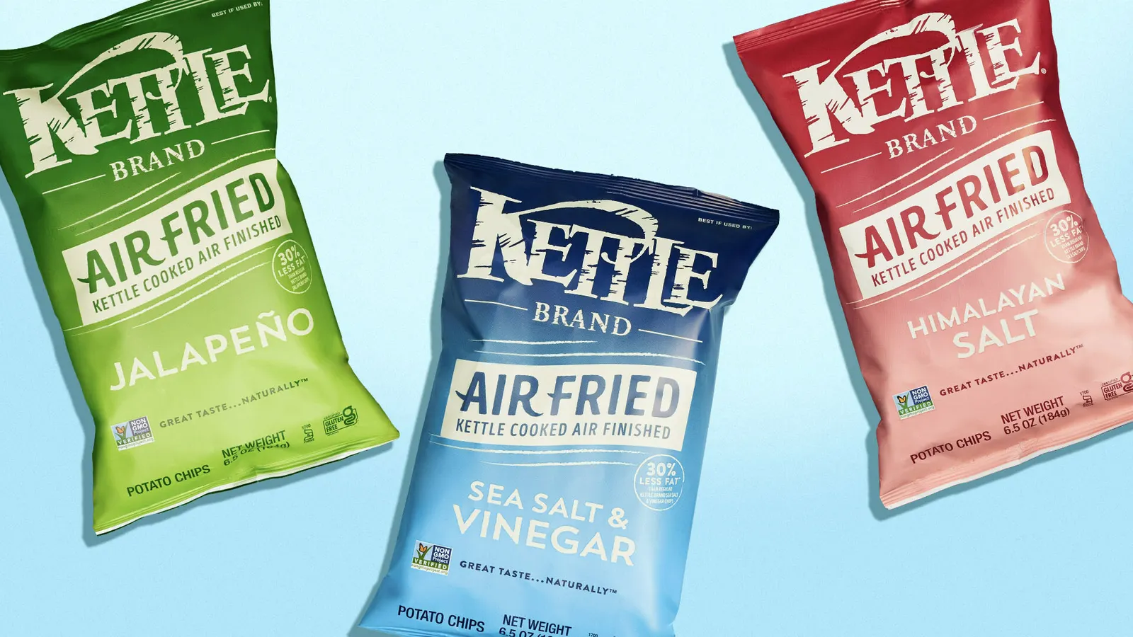Three bags of Kettle Brand Air Fried Chips are lying on a light blue background.