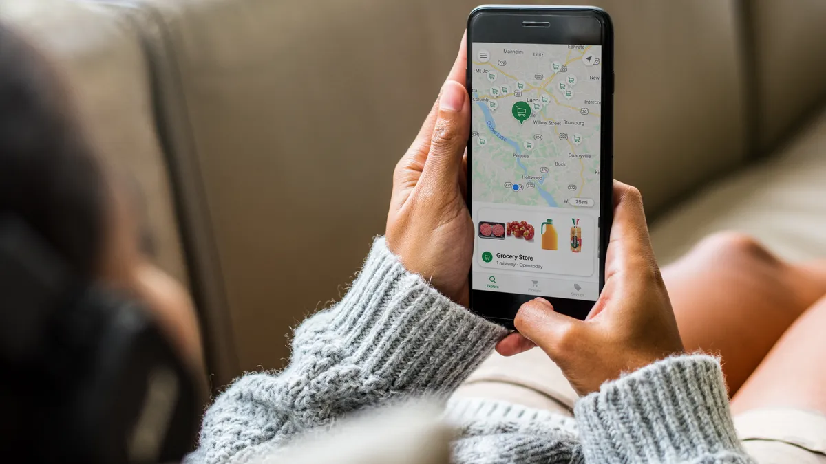 Close-up of hands holding a phone with the screen showing food items below a map