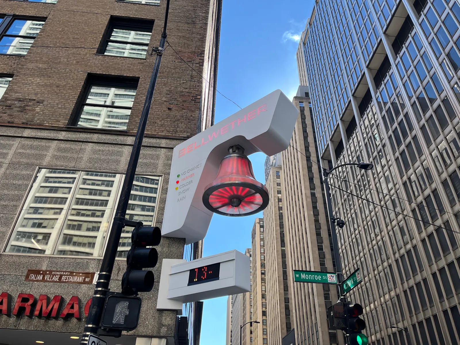 A decoration shaped like a bell with red lights hangs from the side of a building.