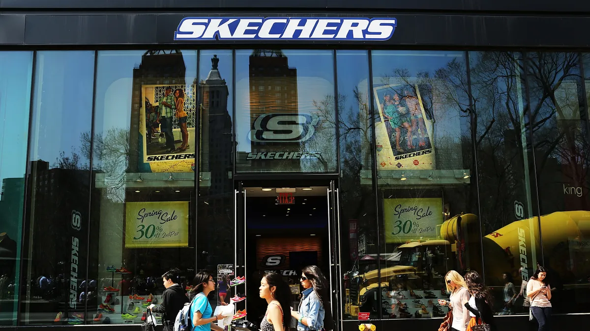 People walk in front of a Skechers store.