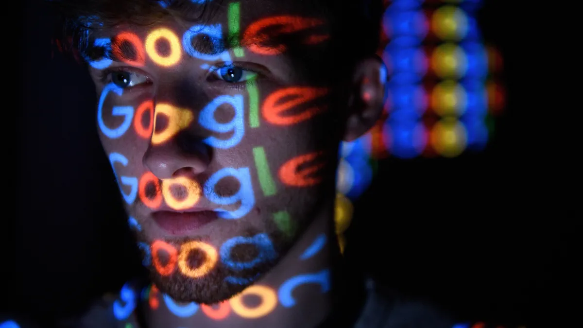 Google's logo is reflected from a screen onto a man