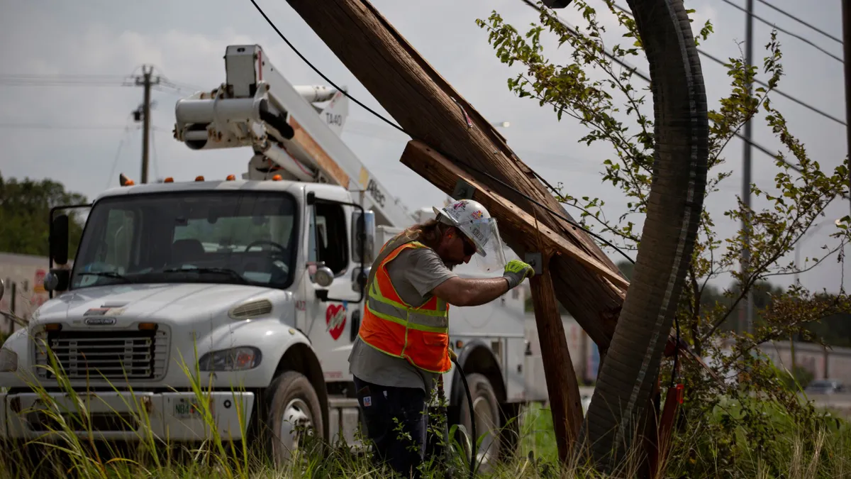 A utility worker inspects a broken power pole