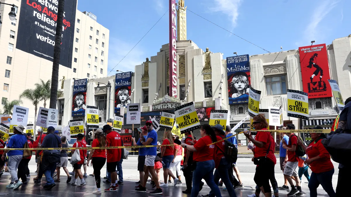 Workers in red T-shirts hold picket signs.