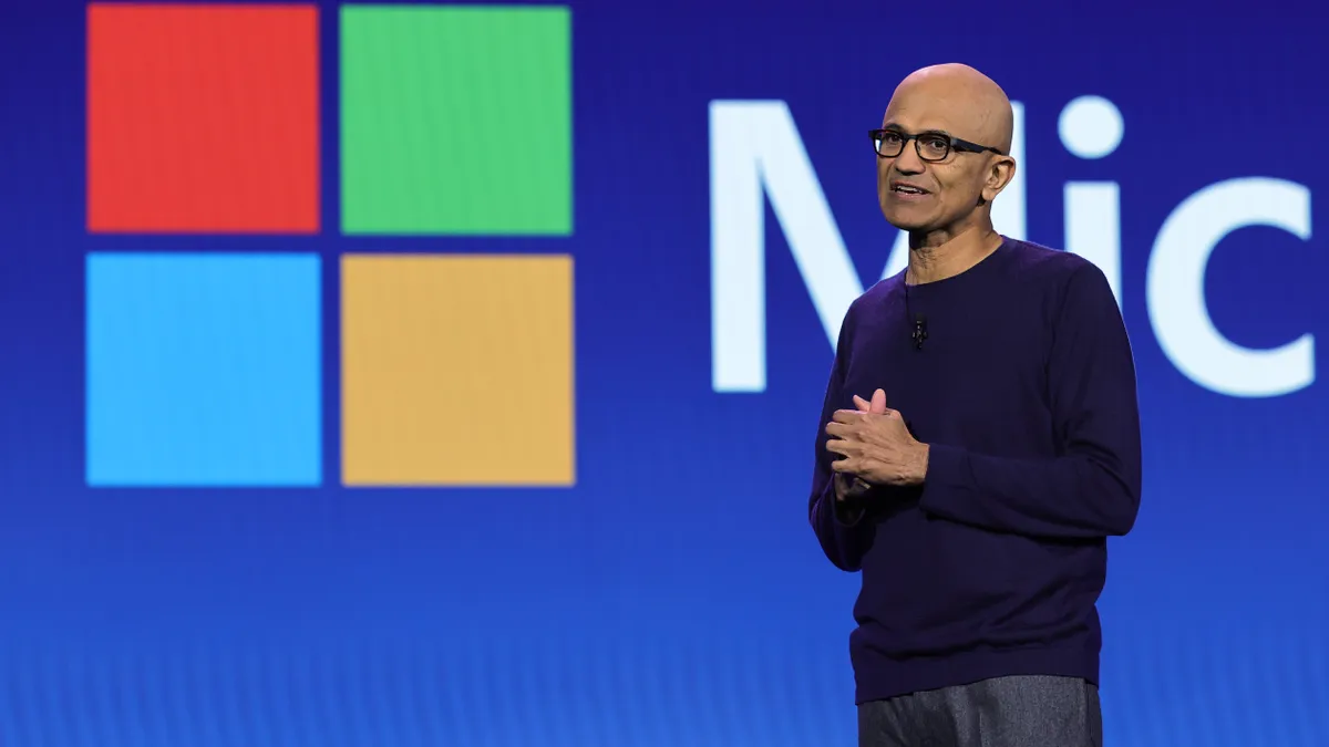 CEO Satya Nadella of Microsoft pictured on stage with the Microsoft logo in the background.