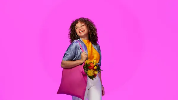Woman with a tote bag in front of a pink background