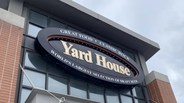 A close up of a black sign with yellow words that say Yard House and great food classic rock and world's largest selection of draft beer.