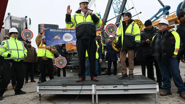 A group of people in construction gear stand at a speaking engagement.