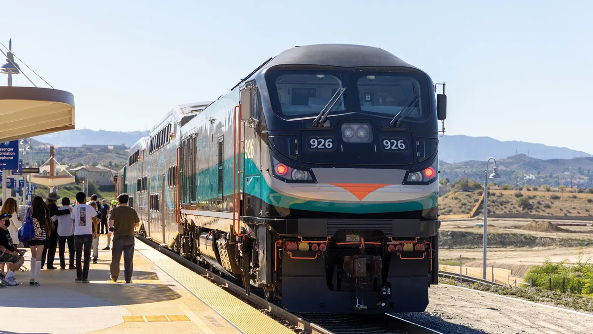 Locomotive and passenger train at a station with many people.