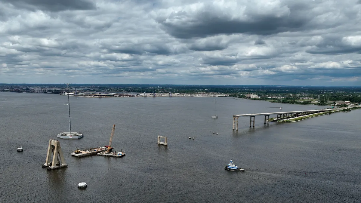 Several barges float around the wreckage of a bridge.