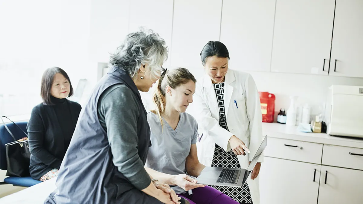 Doctors with patients going over documents on laptop