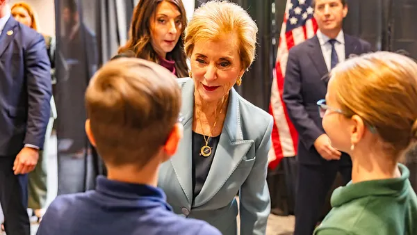 A person is facing the camera and looking at two students, whose backs are toward the camera