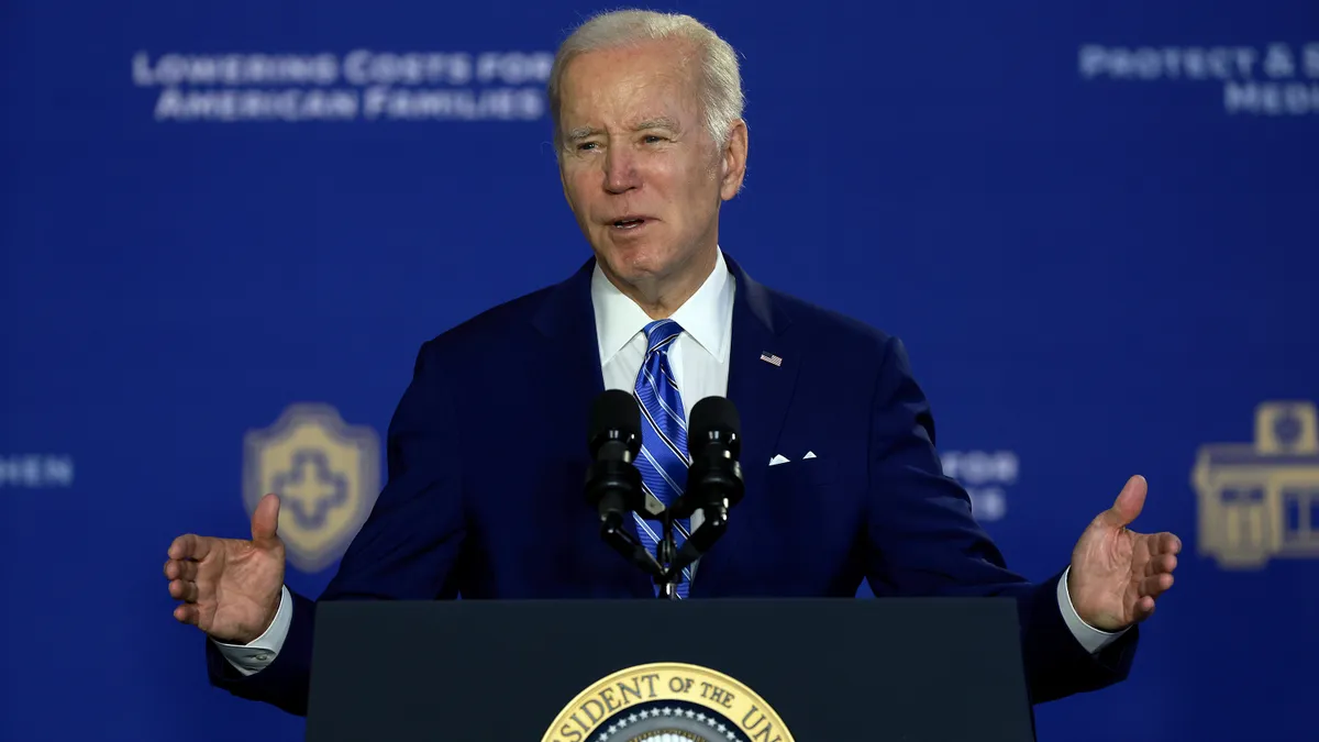 U.S. President Joe Biden gestures with his hands while speaking from behind a podium.