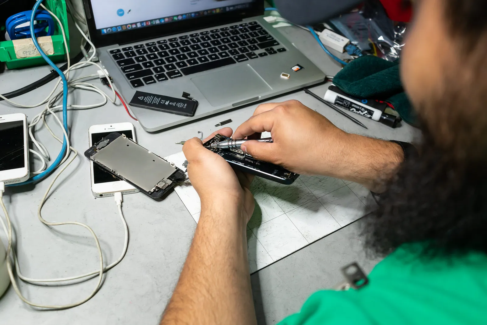 A close-up of an employee using tools to repair a cell phone in a warehouse.