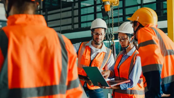 A group of construction pros meet around a laptop.